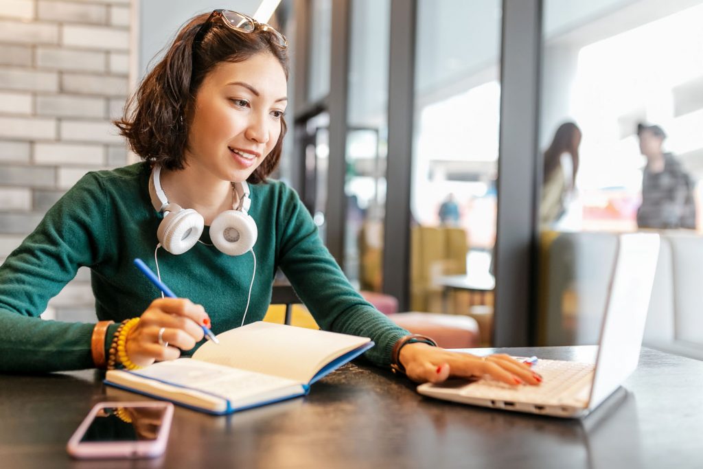 Young Happy Business Asian Woman Taking Notes In Notebook And Working With Laptop Pc Or Computer. Education And Working Concept. Modern Freelance Professions 1024X683